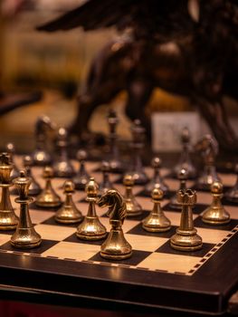 Close-up of an ornate golden chess set with detailed pieces on a board.