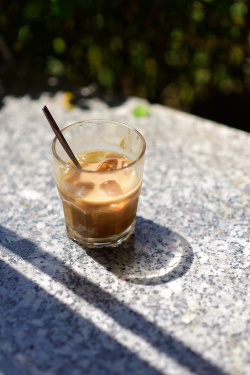 Free Enjoy a glass of iced coffee on a marble table in sunlight with natural shadows. Stock Photo