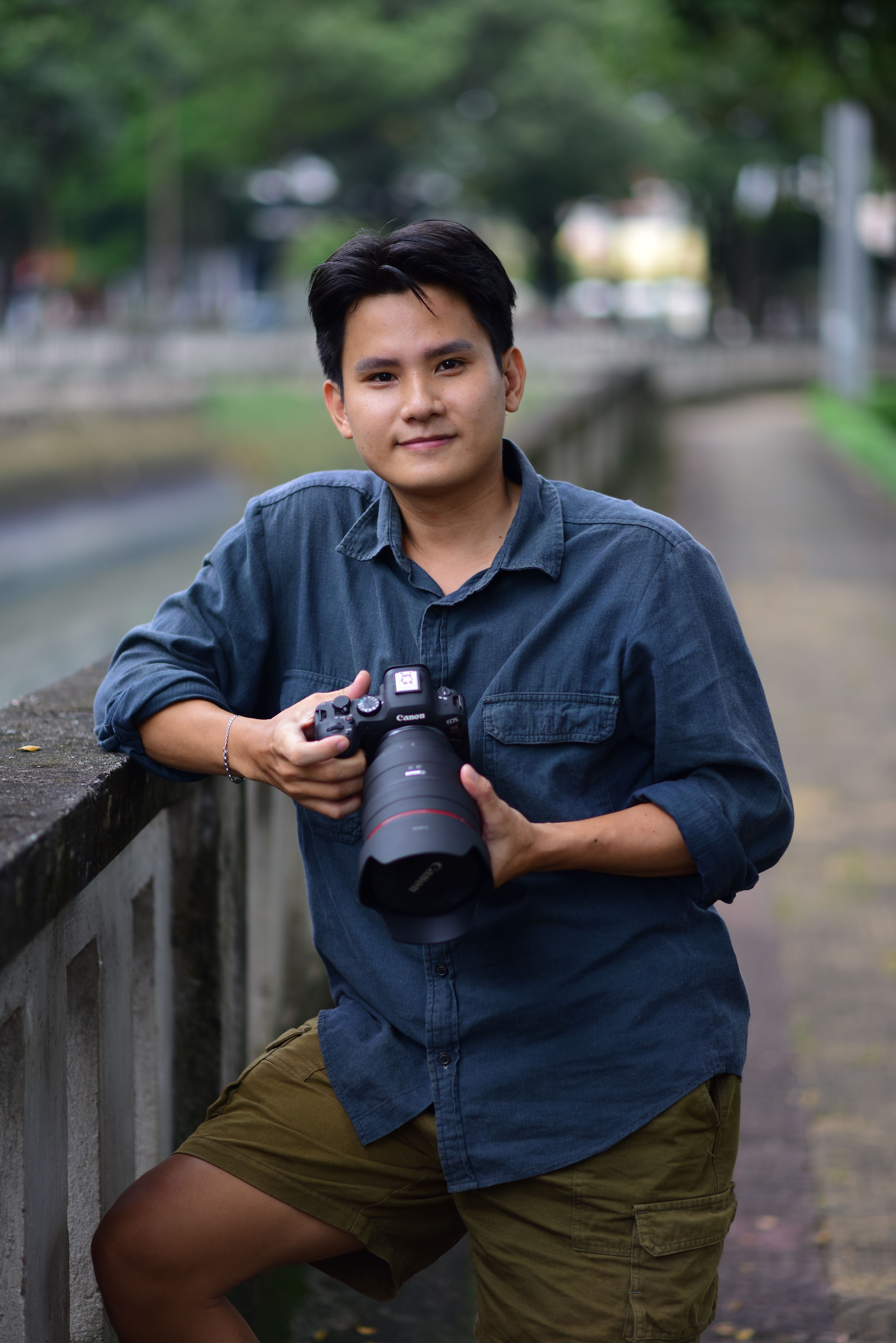 Young photographer standing outdoors with a camera, capturing moments.