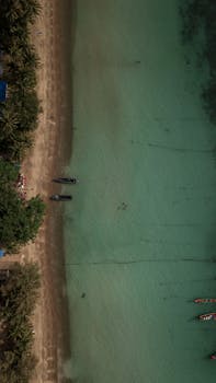 泰国绿松石海岸线的空中拍摄令人惊叹，画面中还有船只和棕榈树