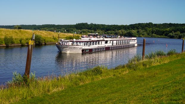 Cruise ship sailing on a picturesque canal in Artlenburg, Germany, on a sunny day.