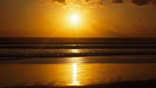 Free A breathtaking golden sunset reflecting on the calm ocean waves at the beach. Stock Photo