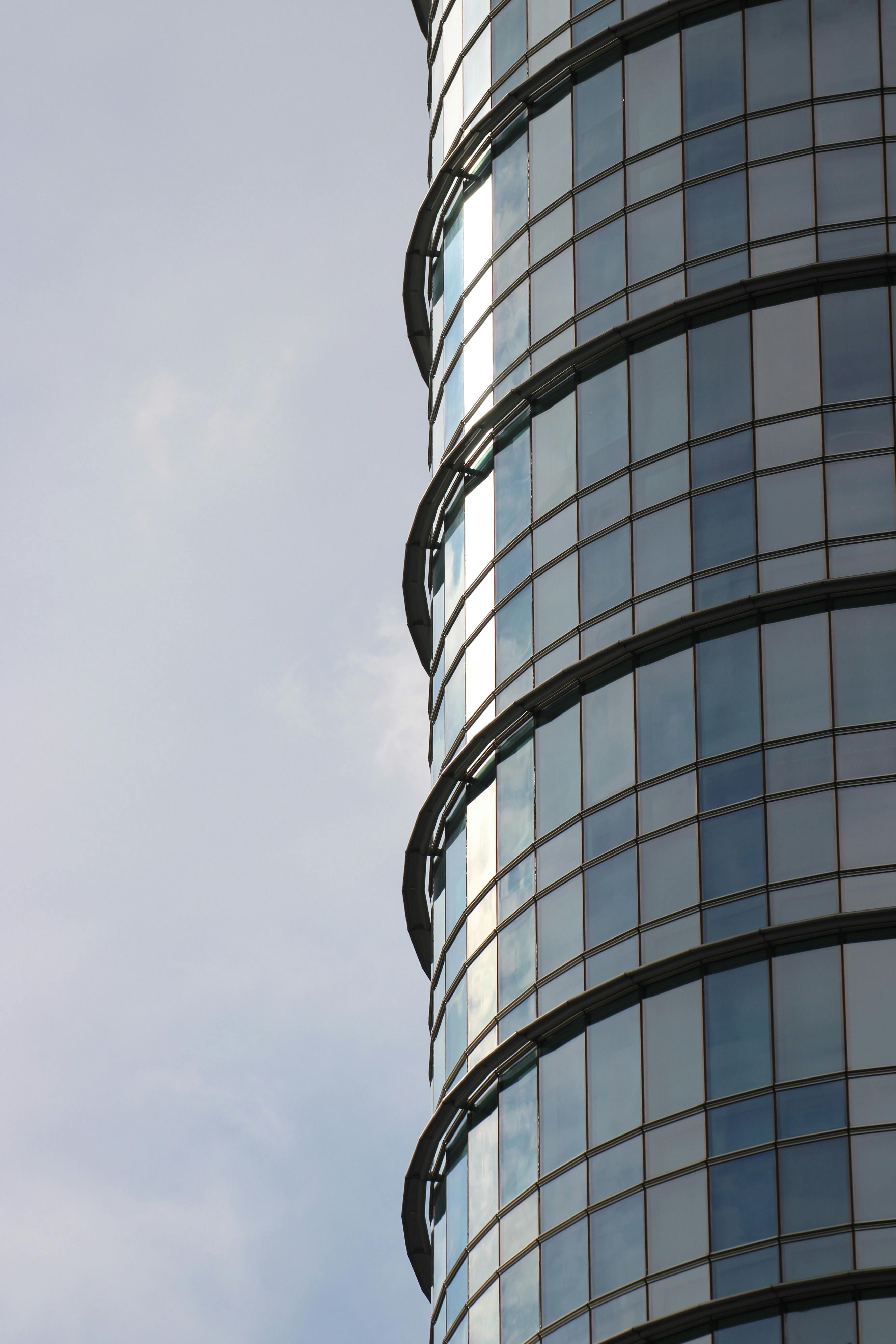 免費 白天特寫一座採用圓形設計的現代玻璃摩天大樓。 圖庫相片