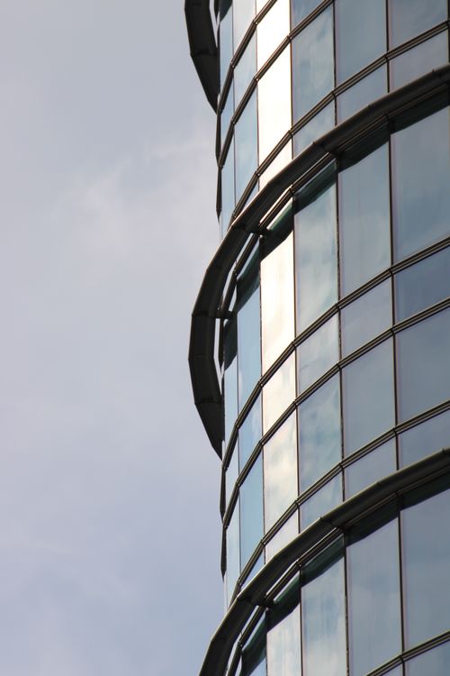 Free Close-up of a modern skyscraper's glass facade reflecting the sky. Stock Photo