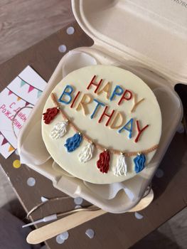 A round birthday cake with vibrant frosting and tassel decorations.