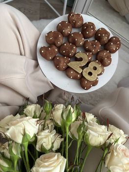Delicious chocolate treats with gold number 28 atop, next to white roses.