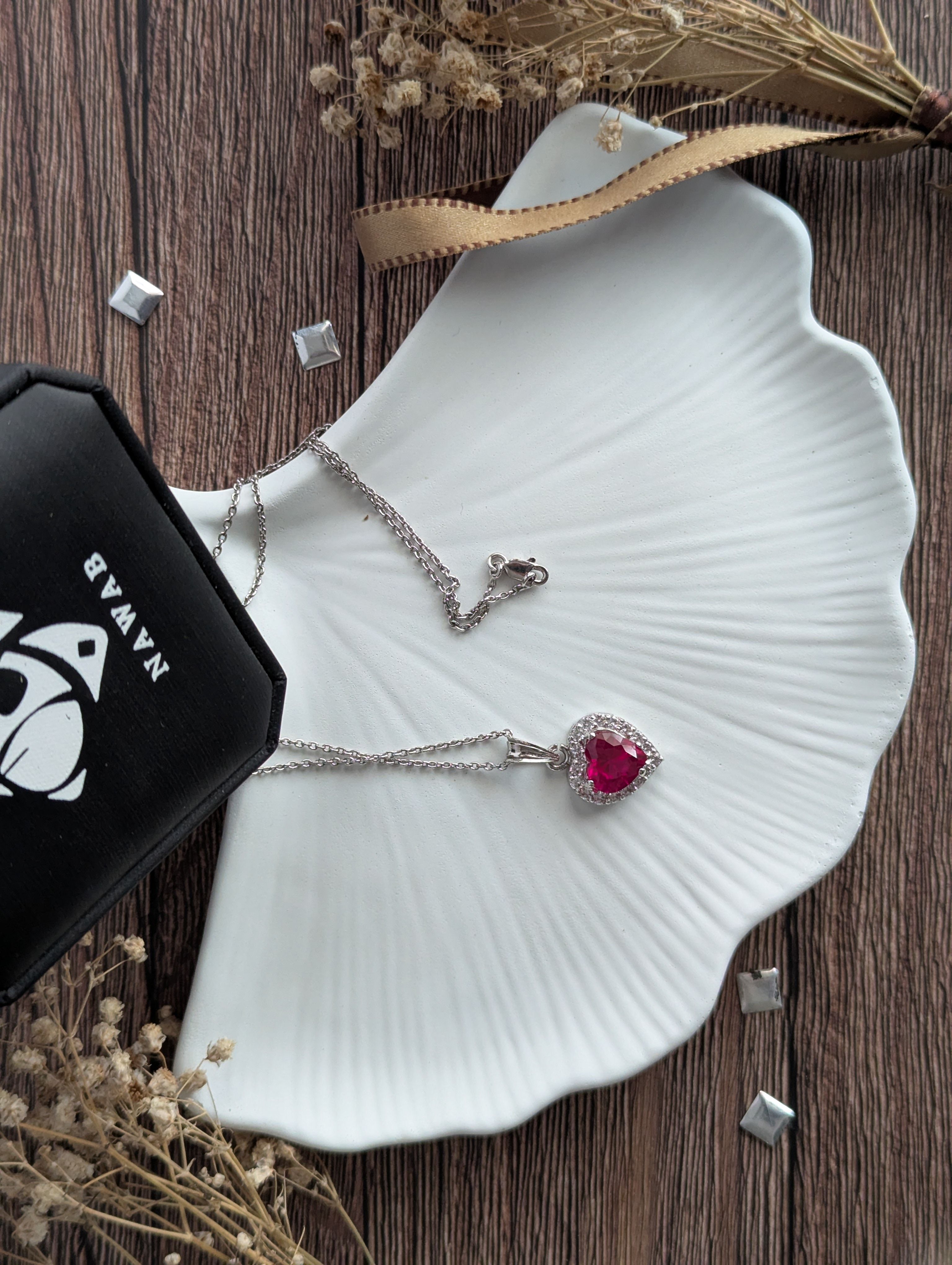 Minimalist silver heart pendant necklace displayed on a shell-shaped plate, perfect for special occasions.