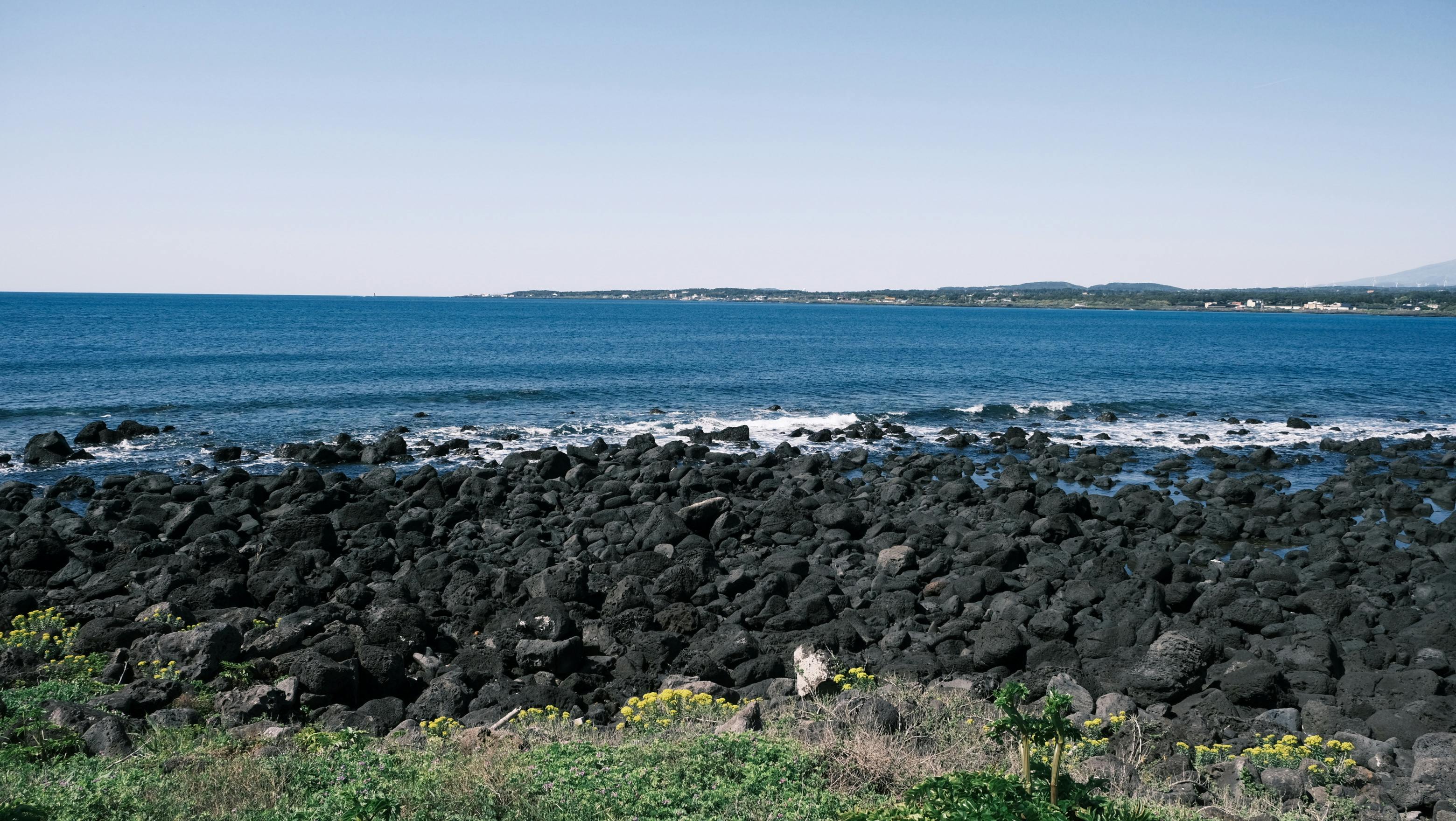 Scenic view of volcanic rocks and blue ocean on Jeju Island, South Korea.