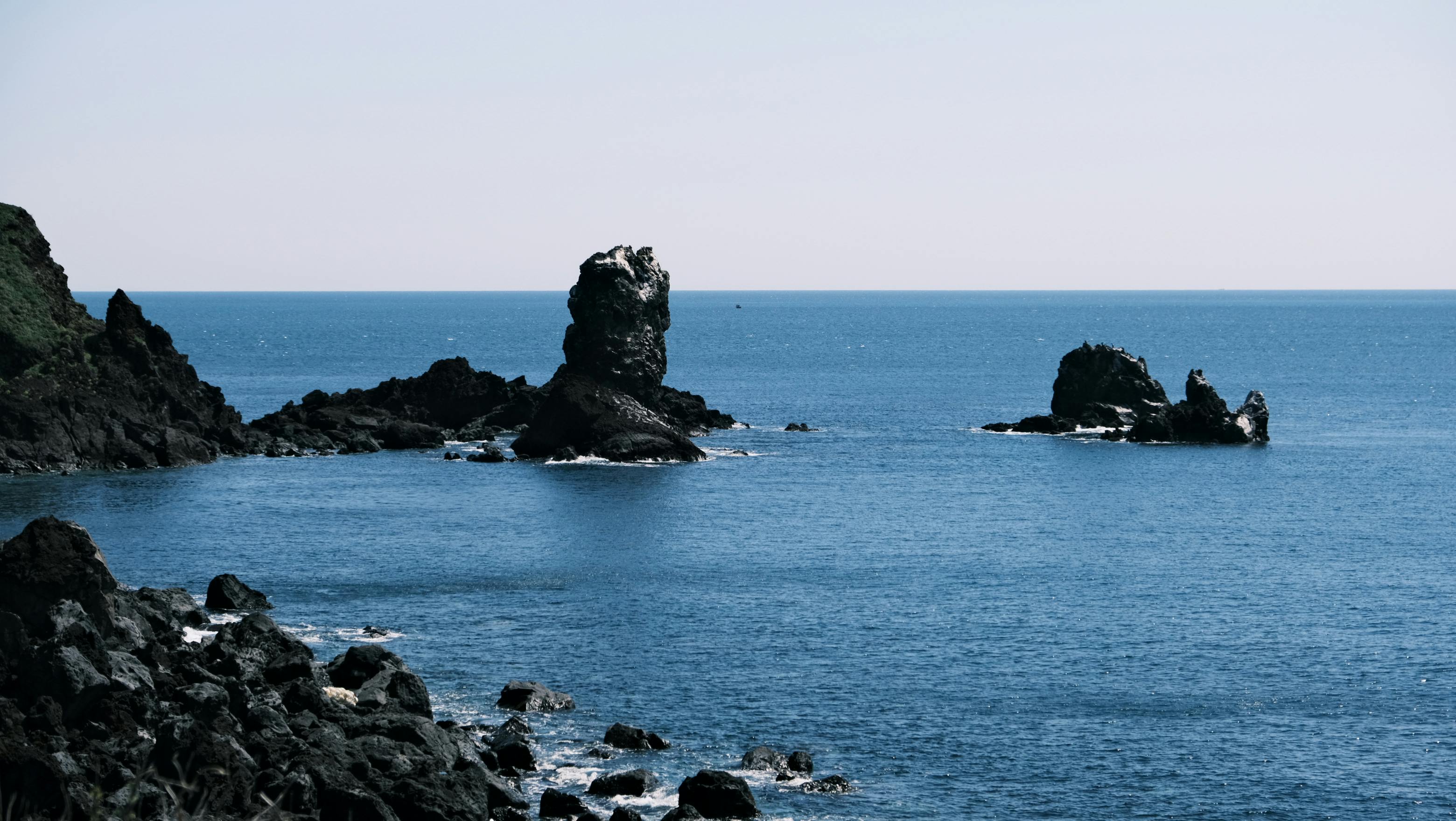 Serene view of rocky coastline and sea stacks on Jeju Island, Korea.