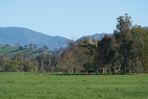 Free Beautiful rural scene with green fields and mountains under a clear sky. Stock Photo
