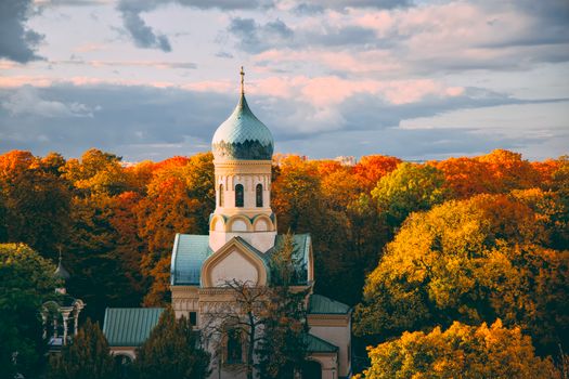 A scenic view of an Orthodox church dome amidst vibrant autumn foliage in Warsaw, Poland.