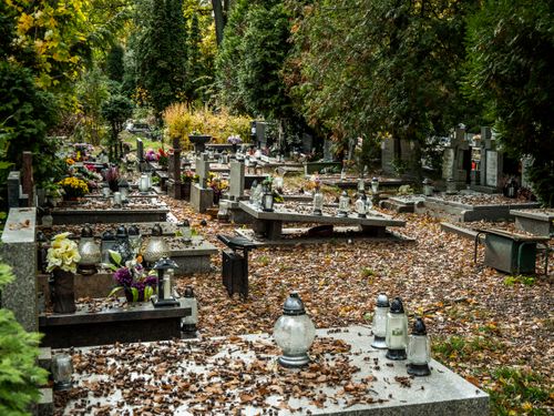 Free Peaceful cemetery in autumn with fallen leaves and lanterns on graves adding a serene atmosphere. Stock Photo