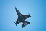 A sleek military jet with striking design flies against a vibrant blue sky, showcasing aerial prowess.