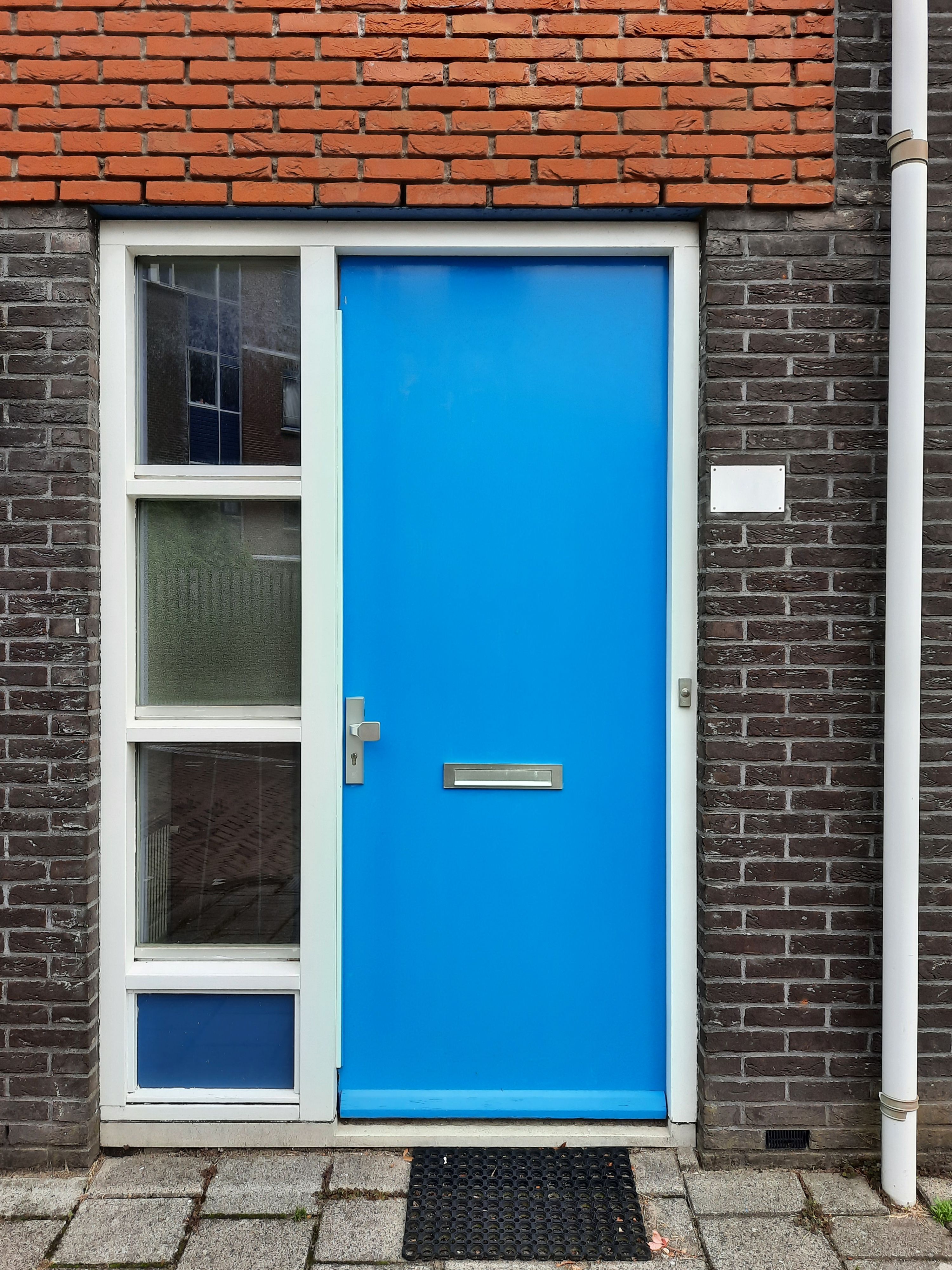 A striking blue door set against classic Dutch brickwork, showcasing modern European architecture.