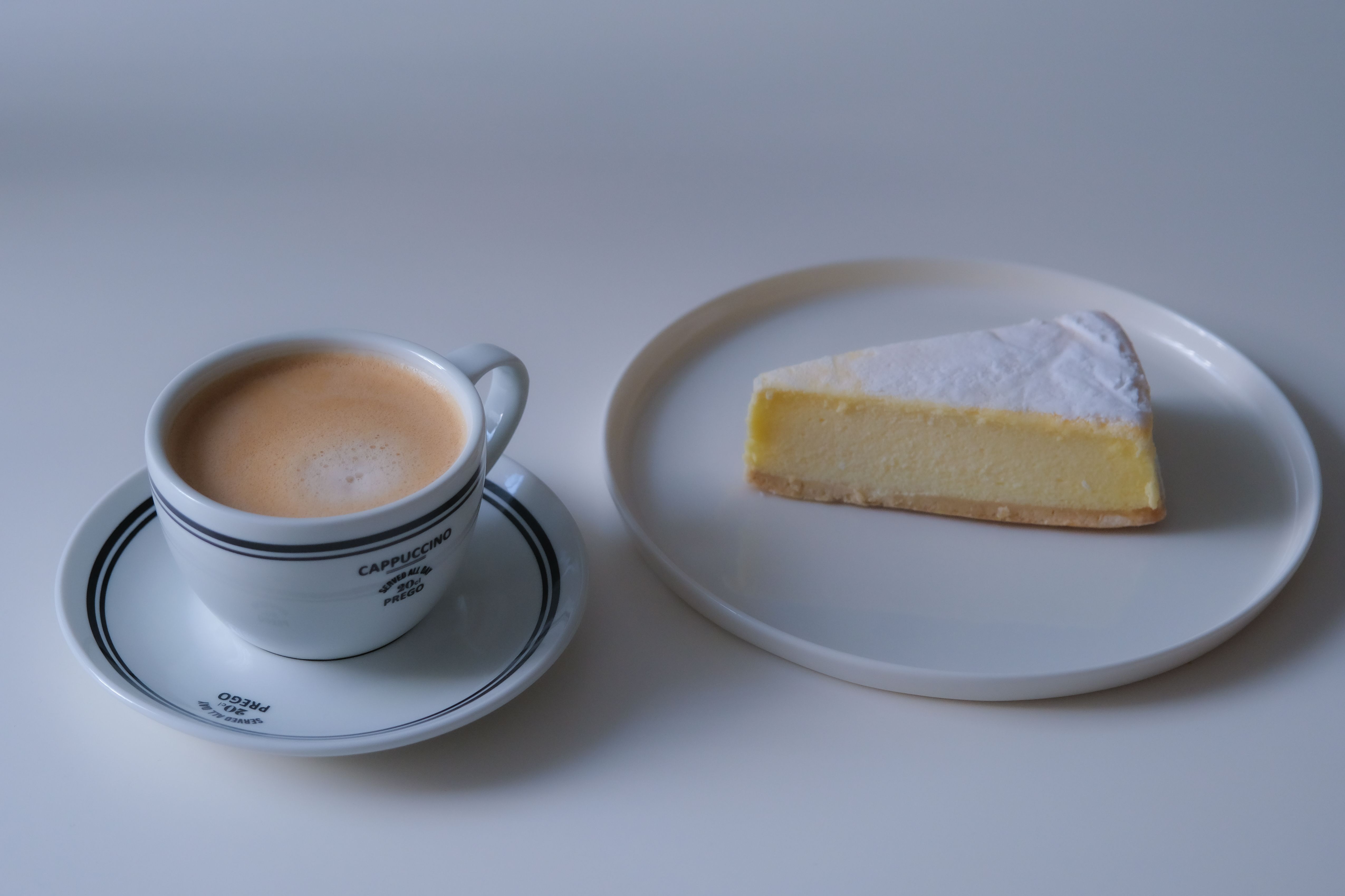 カフェの雰囲気にぴったりな、カプチーノとチーズケーキのエレガントなショット。