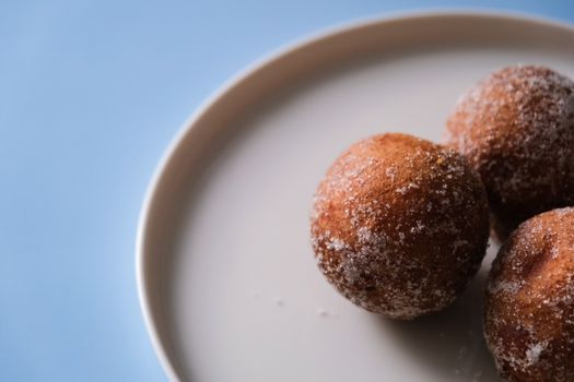 Close-up of sugar-coated pastries on a plate with a blue background.