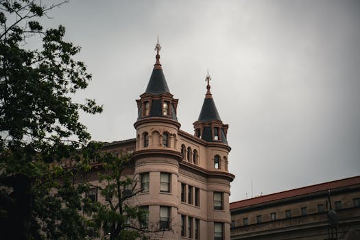 Photograph of a historic building with pointed towers against an overcast sky, showcasing classic architecture.