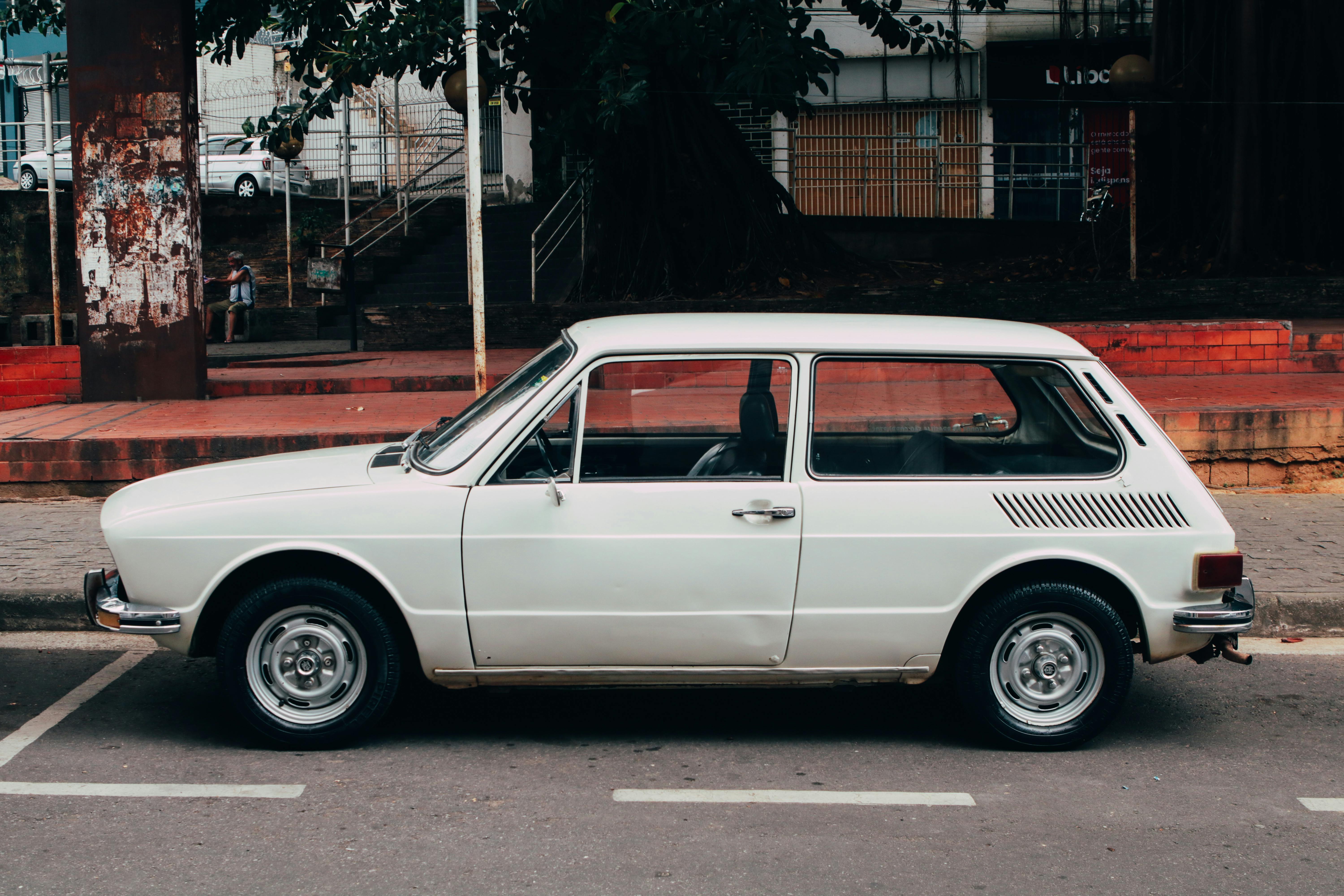 Free Classic white vintage car parked on an urban street during the day. Stock Photo