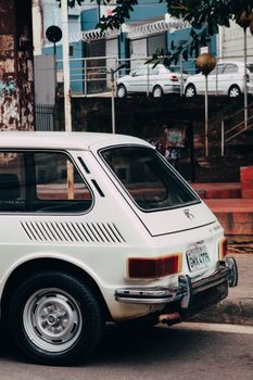 Retro white car parked on urban street, capturing nostalgic design.