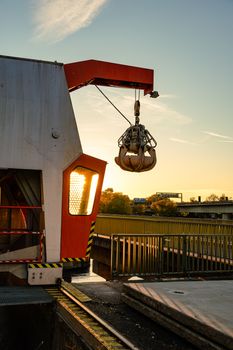 Silhouette of an industrial crane by the water at sunset, creating a dramatic scene.