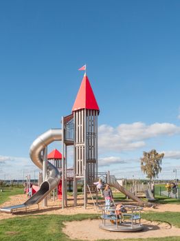 Children enjoy a sunny day at a vibrant outdoor playground with slides and merry-go-round.