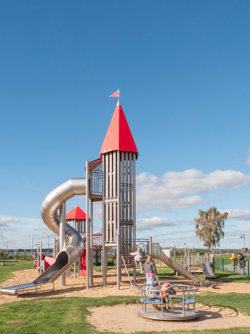 Children enjoy a sunny day at a vibrant outdoor playground with slides and merry-go-round.