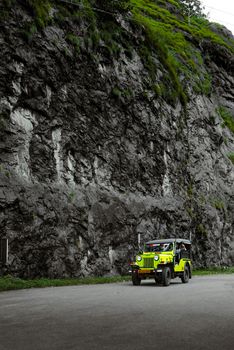 Vibrant yellow jeep on scenic mountain road in Idukki, Kerala, India.