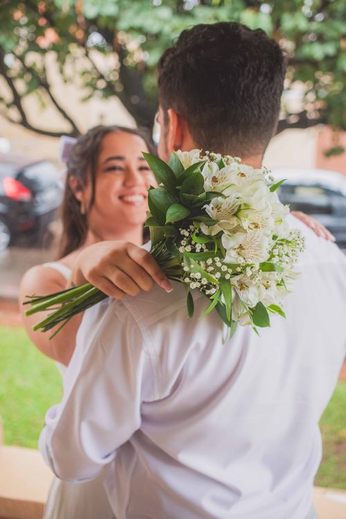 Free Joyful bride holding bouquet while embracing groom outdoors. Stock Photo