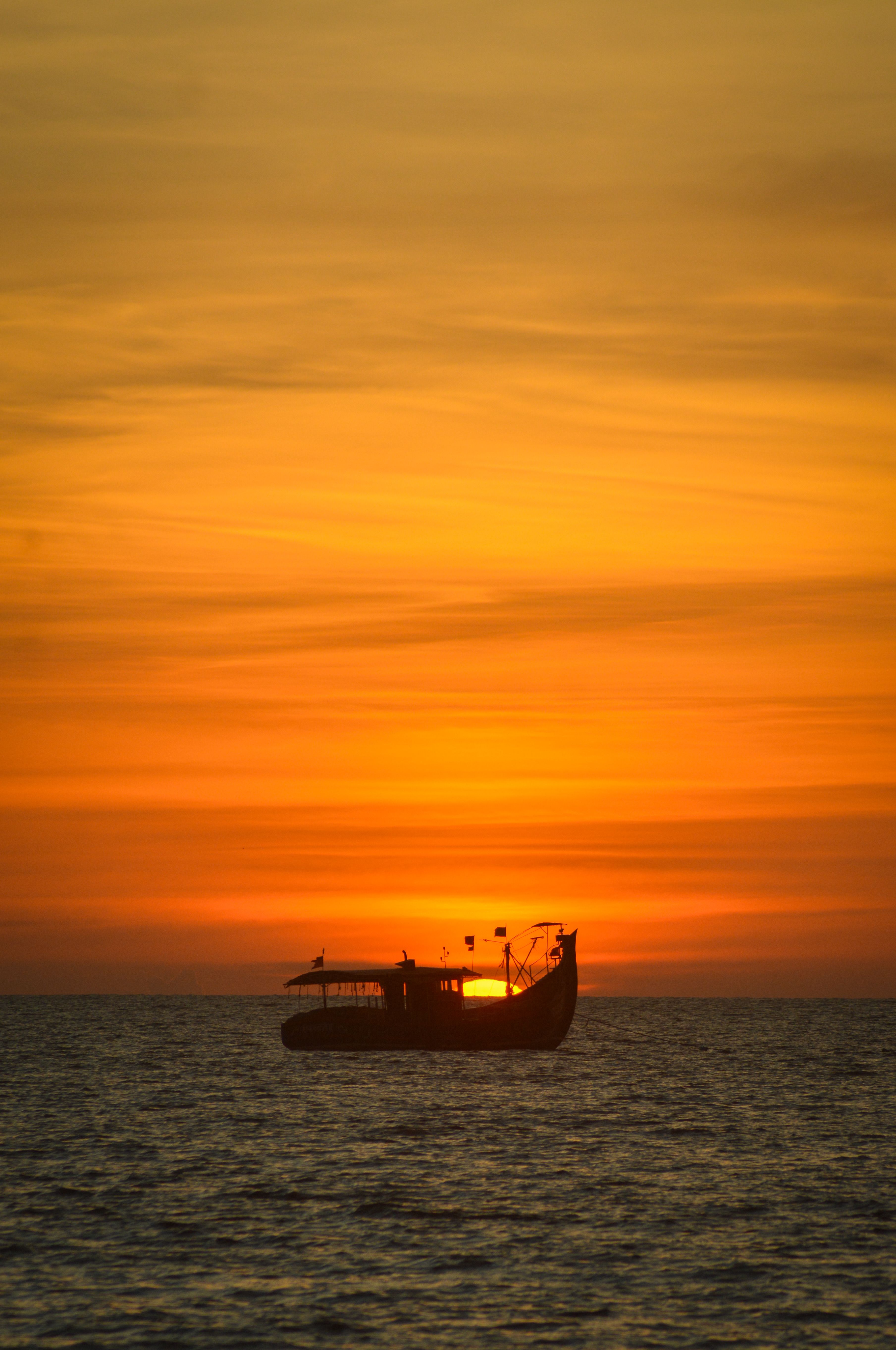 Serene Sunset Silhouette of a Boat at Sea · Free Stock Photo