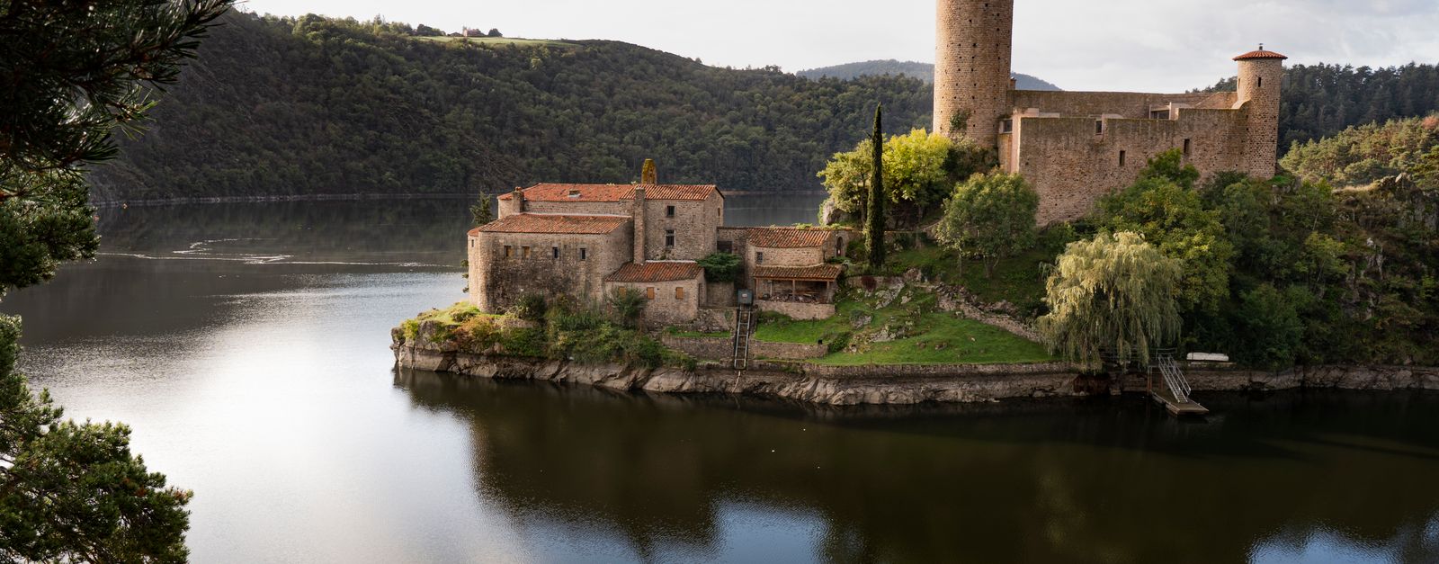 Picturesque view of Château de Grangent surrounded by serene waters in Auvergne-Rhône-Alpes.