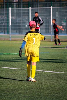 Young goalkeeper in a soccer game ready to play. Sunlit field with vibrant energy and focus.