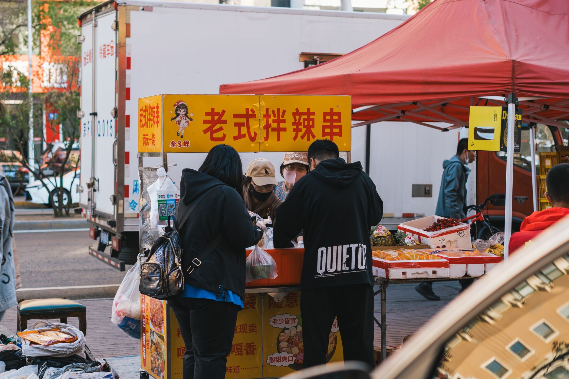 Lively street food scene in Harbin, China with a bustling vendor and colorful market stall.