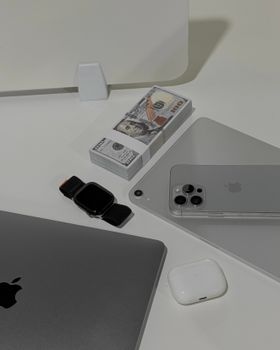 Top view of tech gadgets and cash on a minimal white desk. Modern and elegant workspace aesthetic.