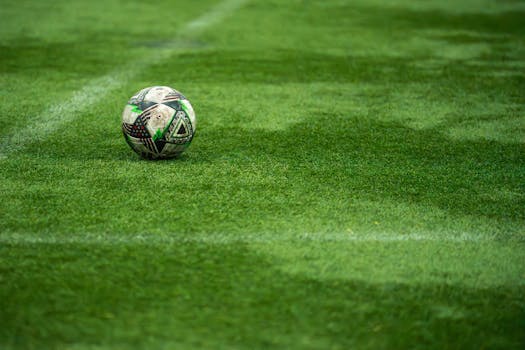 Close-up of a soccer ball resting on a vibrant green turf field, perfect for sports image needs.