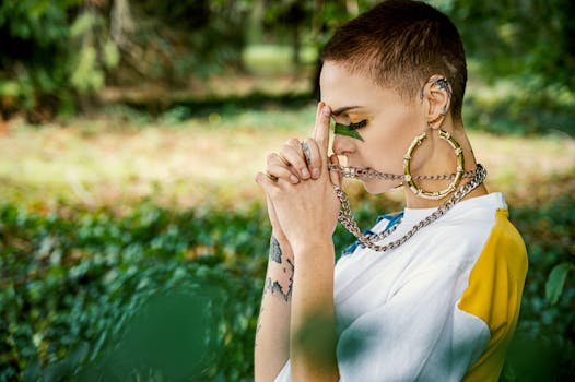 Side view of a stylish young woman meditating outdoors, wearing bold accessories and a fashionable outfit.