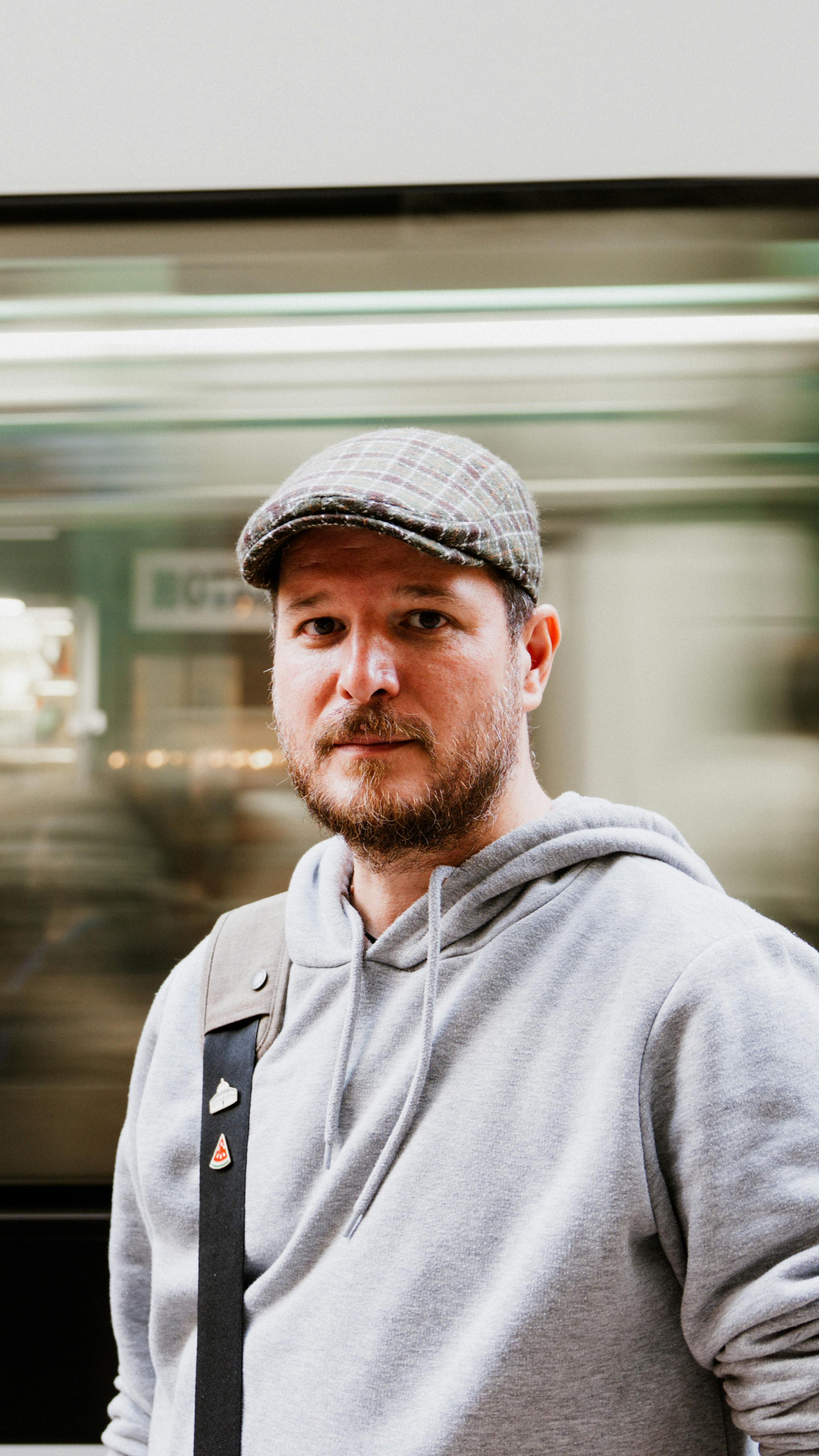 Man in a casual outfit with a blurred background, creating a dynamic urban portrait.