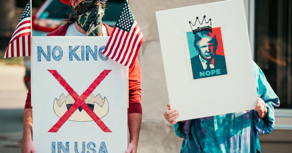 Photo by Chris F Two protesters displaying political signs during a demonstration with US flags.