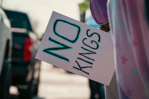Free Protester holds a sign with 'No Kings' message during street demonstration. Stock Photo