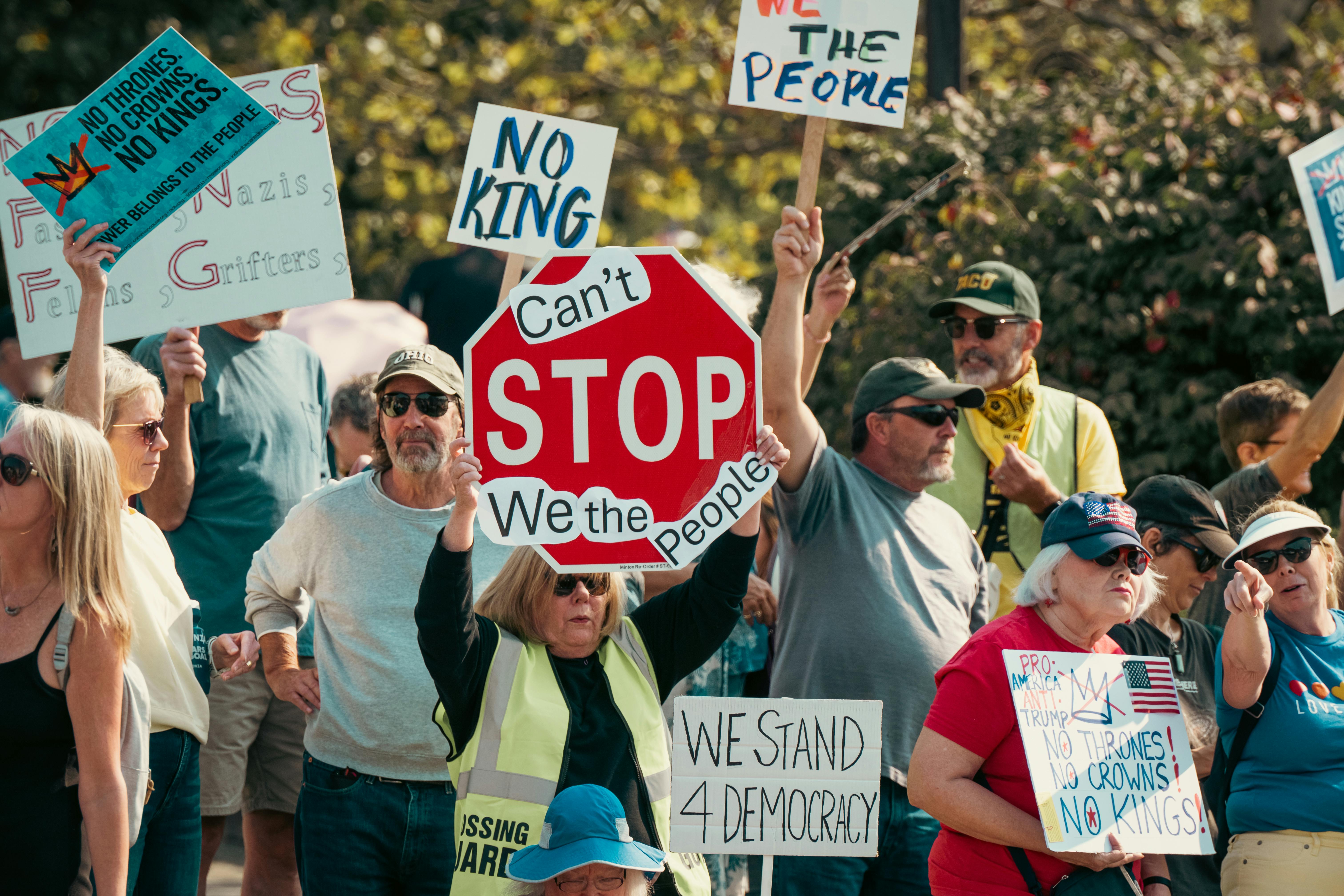 Group of people holding signs at a democracy protest emphasizing unity and change.