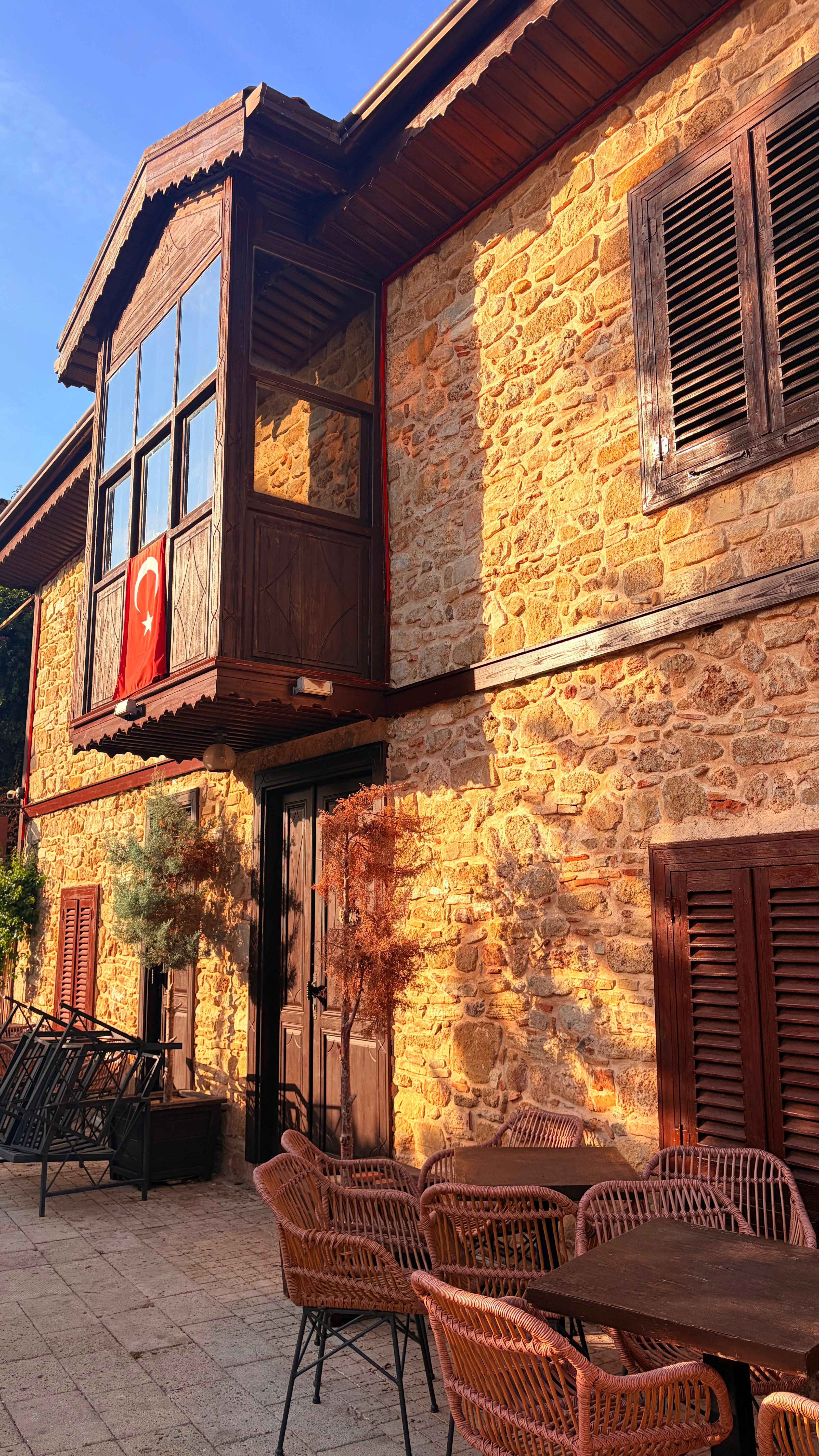 Sunlit stone house with traditional Turkish architecture and patio seating in Antalya.