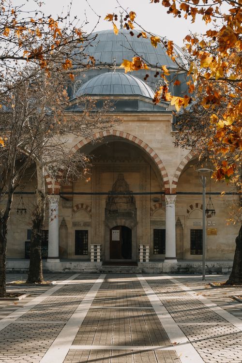 Free A picturesque mosque with a large dome amidst autumn trees, featuring warm sunlight. Stock Photo