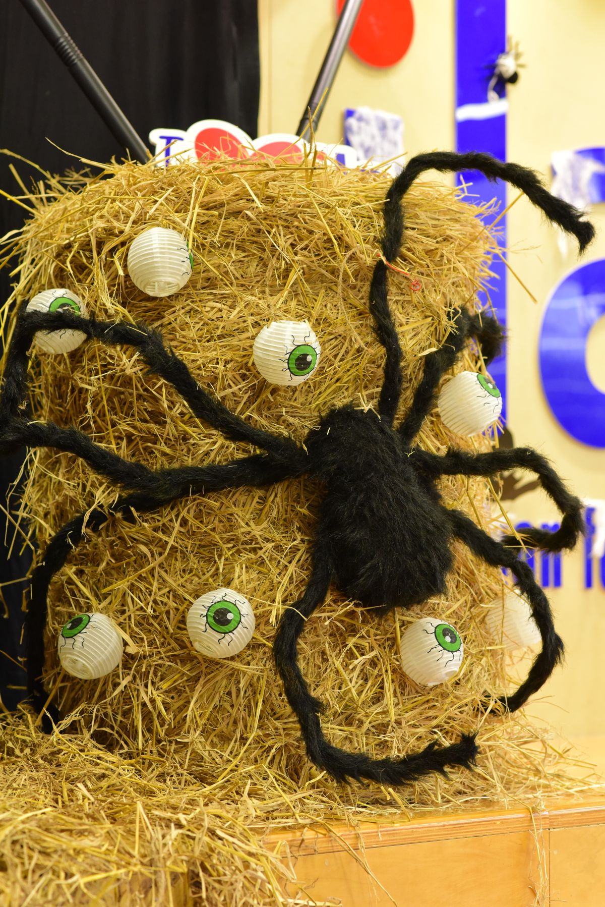 A Halloween hay bale topped with a giant spider and eyeball decorations