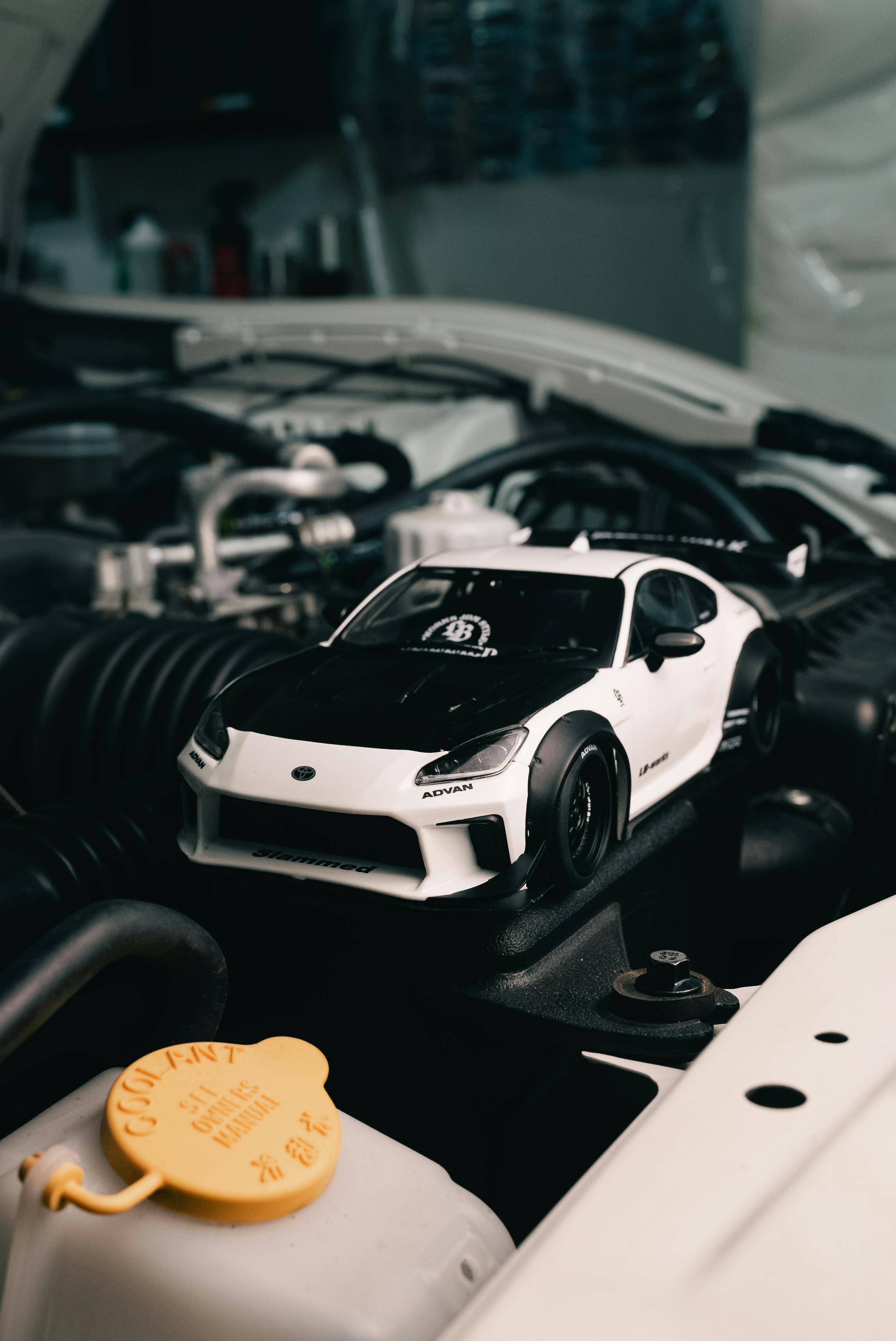 Gratis Tampilan dekat mobil sport mainan yang diletakkan di atas mesin mobil sungguhan, memamerkan detail yang rumit. Foto Stok