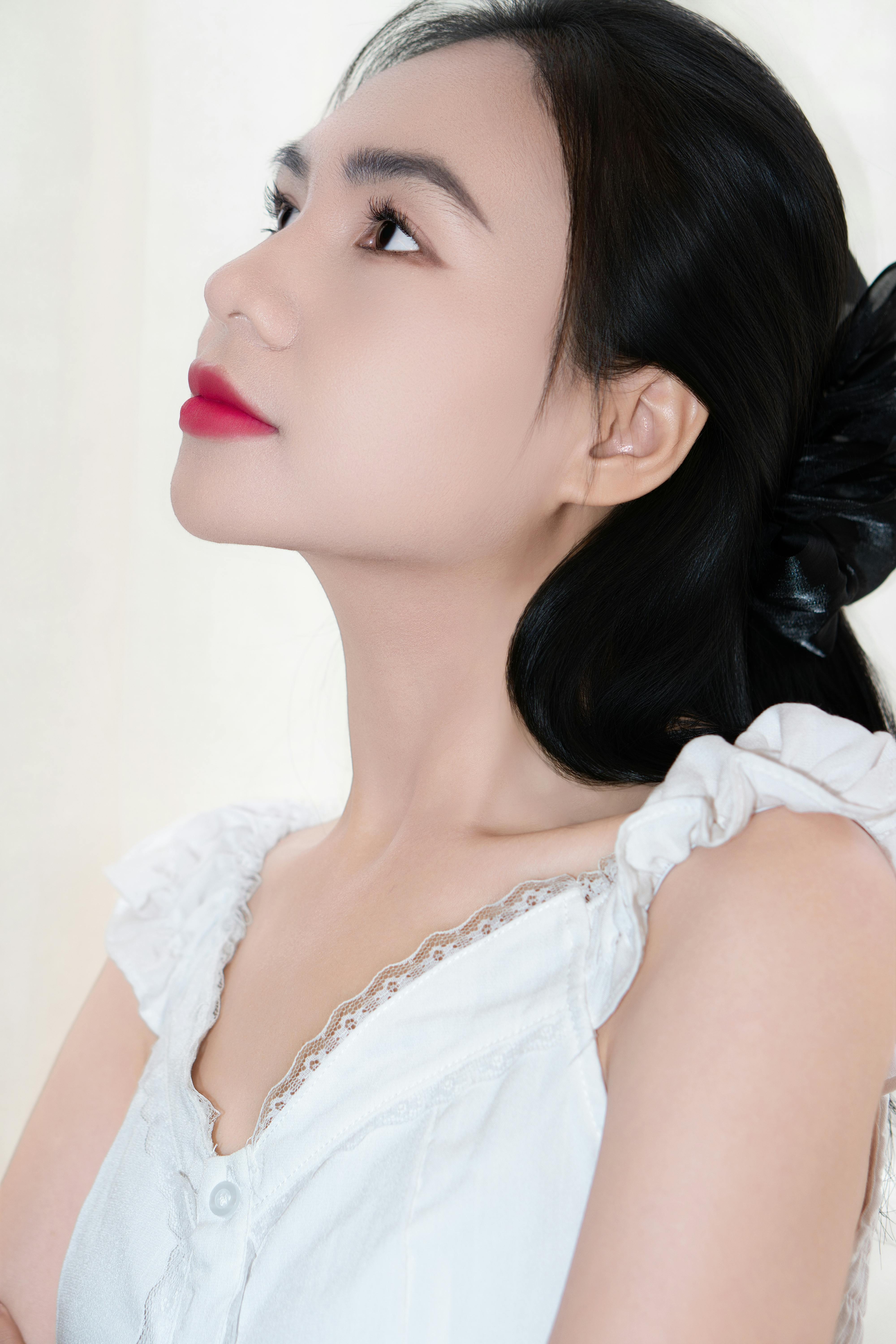 Profile portrait of a woman with red lips, looking upwards with elegance and grace.