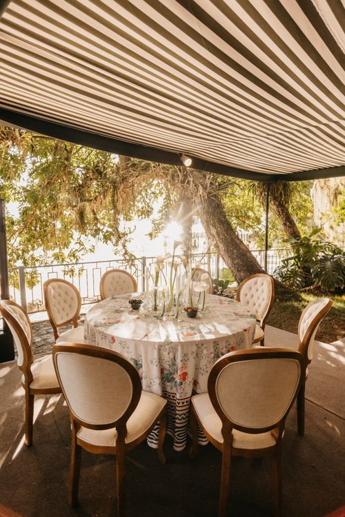Free Charming outdoor dining area with elegant chairs under a striped awning, perfect for summer gatherings. Stock Photo