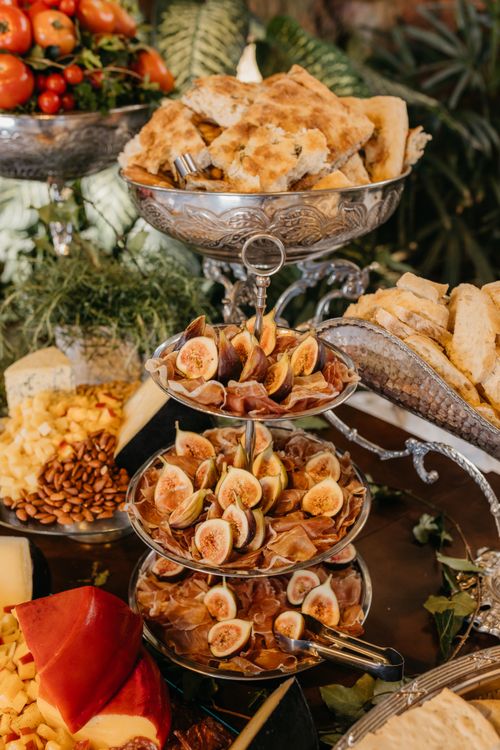 Free A lavish display of Mediterranean cuisine featuring fresh figs, bread, and cheese on ornate silver platters. Stock Photo