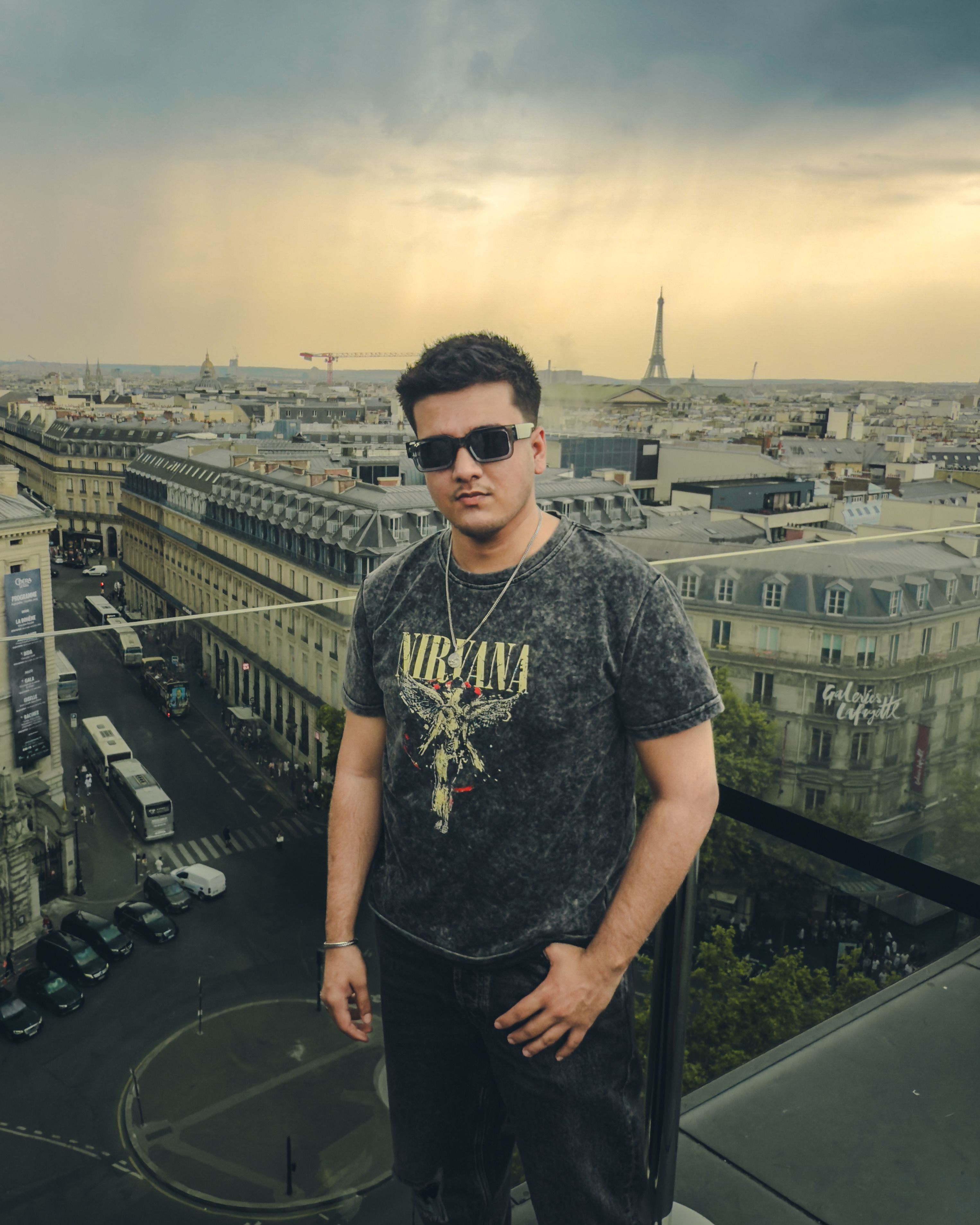 A trendy man on a rooftop with Paris skyline in the background, featuring the Eiffel Tower during sunset.