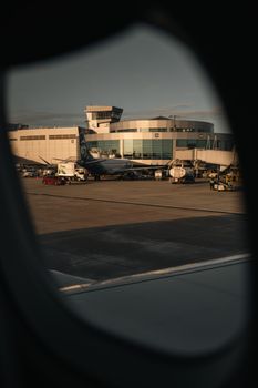 Airport terminal captured from airplane window during day. Suitable for travel and aviation themes.