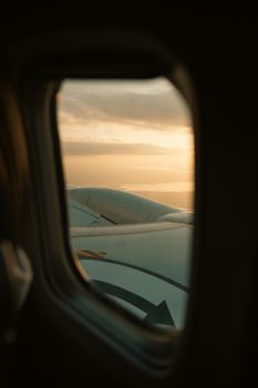 A tranquil sunset view from an airplane window, capturing the wing and horizon.