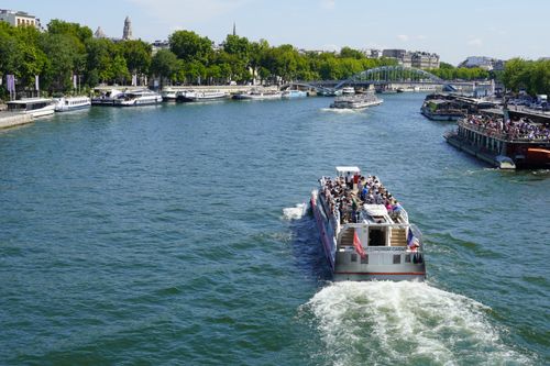 Free A vibrant scene of a tourist boat cruising on the Seine River in Paris during a sunny day. Stock Photo